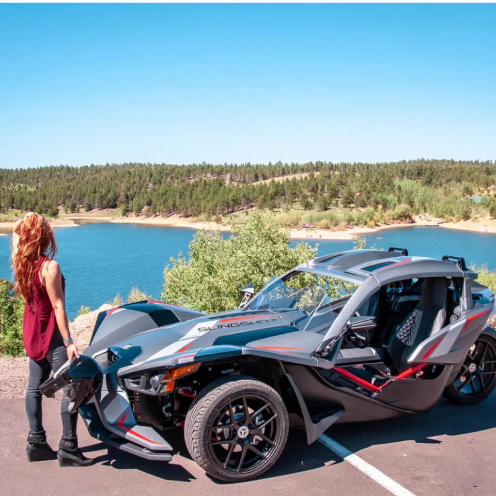 woman in red standing in front of a grey slingshot