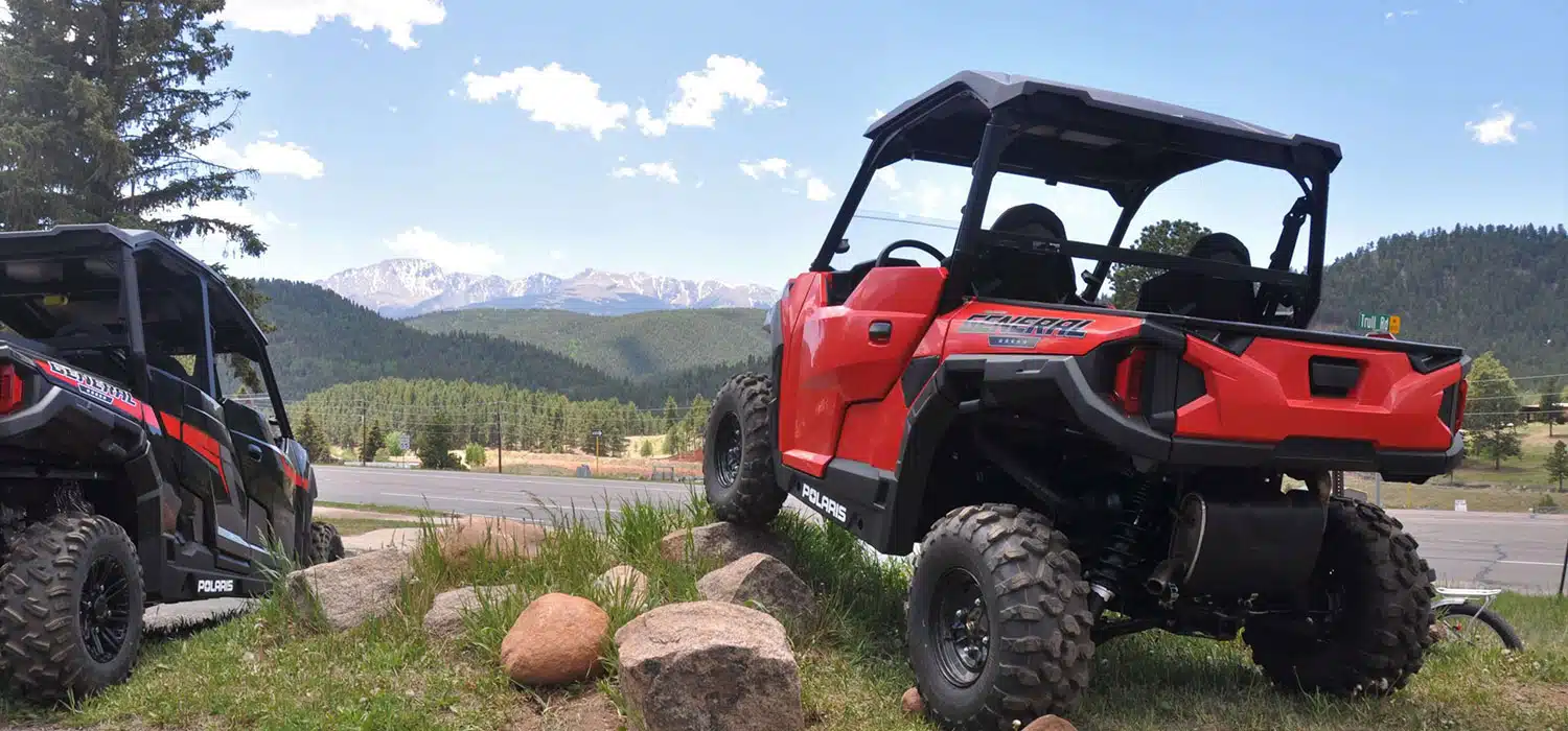 Red UTV with wheels on top of a rock