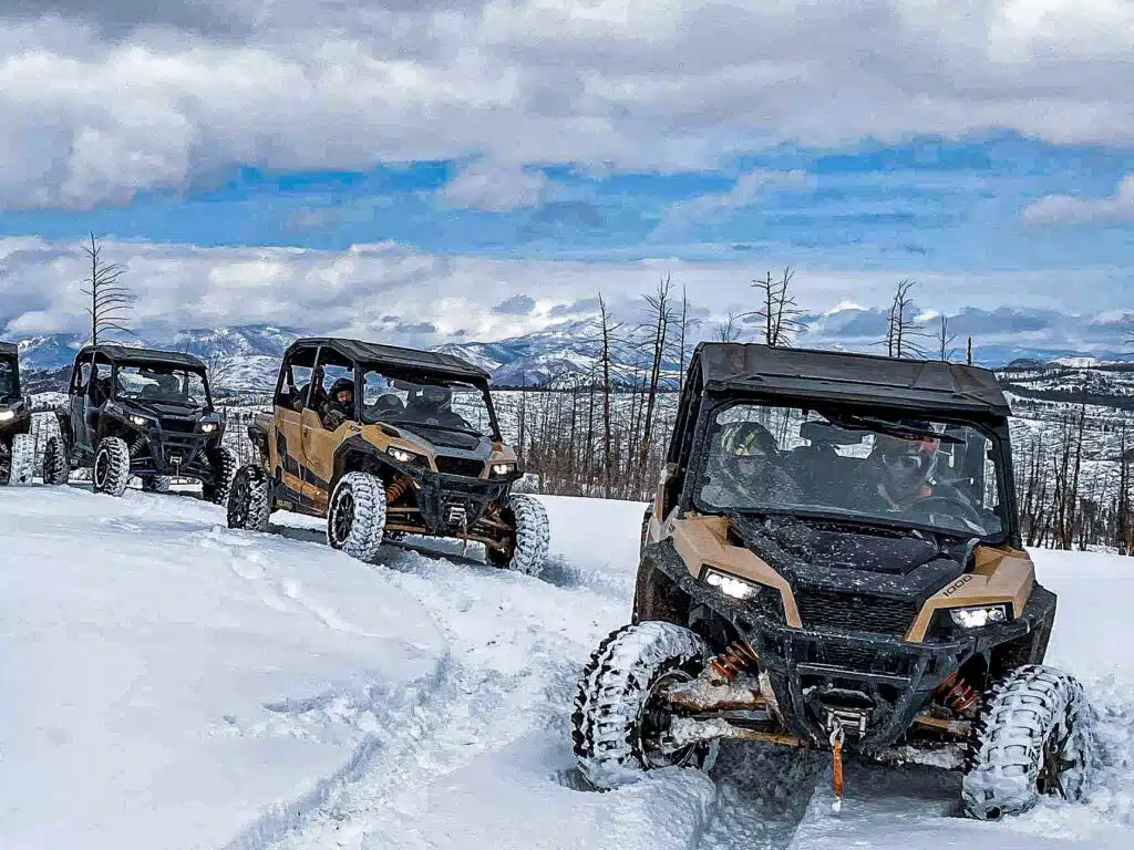 Group of UTVs driving through snowy trails in the mountains near Woodland Park, Colorado, enjoying a guided winter adventure with Great Outdoors Adventures.