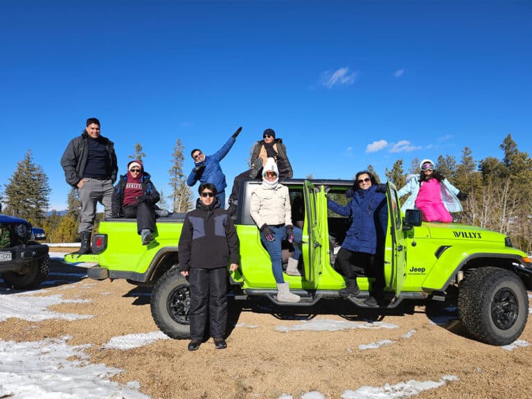 Jeep Gladiator en un tour invernal guiado de Great Outdoors Adventures en el Bosque Nacional Pike, navegando por carreteras rurales nevadas en Colorado.