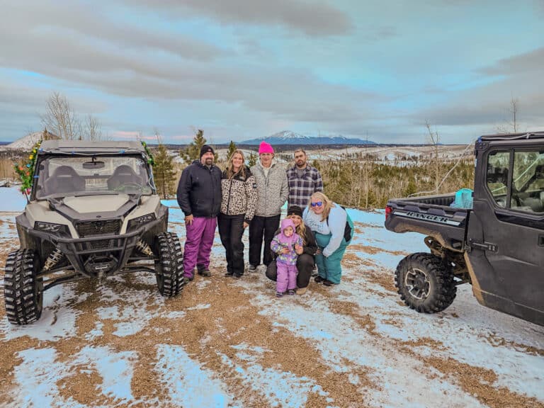 “Grupo disfrutando de un alquiler de UTV todoterreno en Colorado en invierno con senderos cubiertos de nieve, Pikes Peak de fondo y varios UTV en una aventura guiada en UTV en Colorado que muestra un terreno todoterreno panorámico en UTV