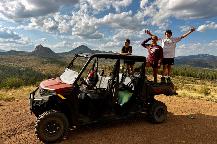 Kids and teens posing on a 6-seater Polaris Ranger Crew UTV rental at a mountain scenic overlook near Woodland Park Colorado