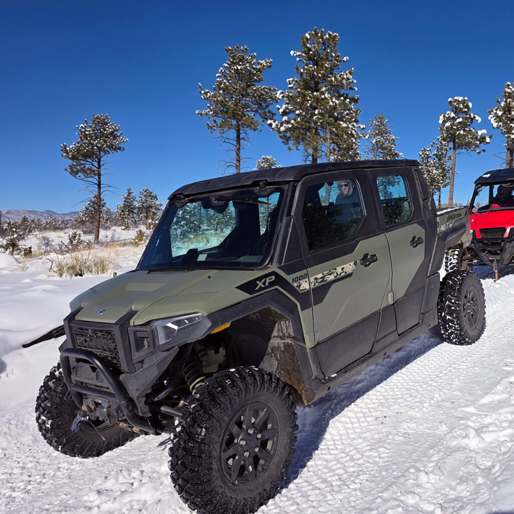 Enclosed climate-controlled Polaris Expedition UTV rental parked on a snowy trail under a clear blue sky near Woodland Park Colorado